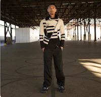 a man in a black and white sweater standing in a warehouse