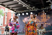 two women singing on stage at an outdoor event