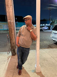 a man leaning against a pole at night