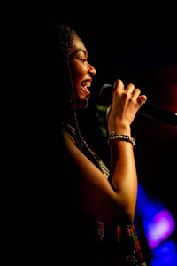 a woman singing into a microphone in a dark room